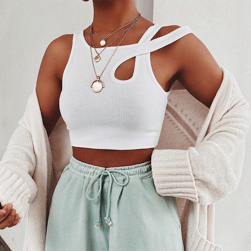 Person wearing a white crop top, light green pants, and a beige cardigan with layered necklaces.